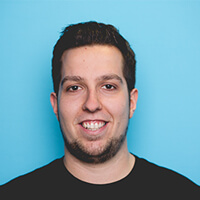 Portr&auml;t von Jeffrey Reichardt, der in die Kamera blickt und dabei l&auml;chelt; vor einem hellblauen Hintergrund.