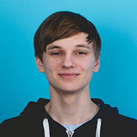 Portr&auml;t von Aaron Pietscher, der in die Kamera blickt und dabei l&auml;chelt; vor einem hellblauen Hintergrund.