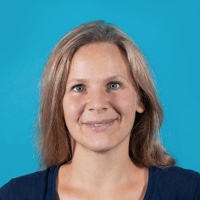 Portr&auml;t von Mareike Thiele, die in die Kamera blickt und dabei l&auml;chelt; vor einem hellblauen Hintergrund.