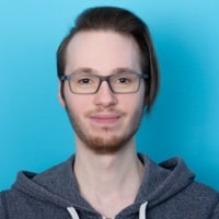 Portr&auml;t von Tobias Seifert, der in die Kamera blickt und dabei l&auml;chelt; vor einem hellblauen Hintergrund.